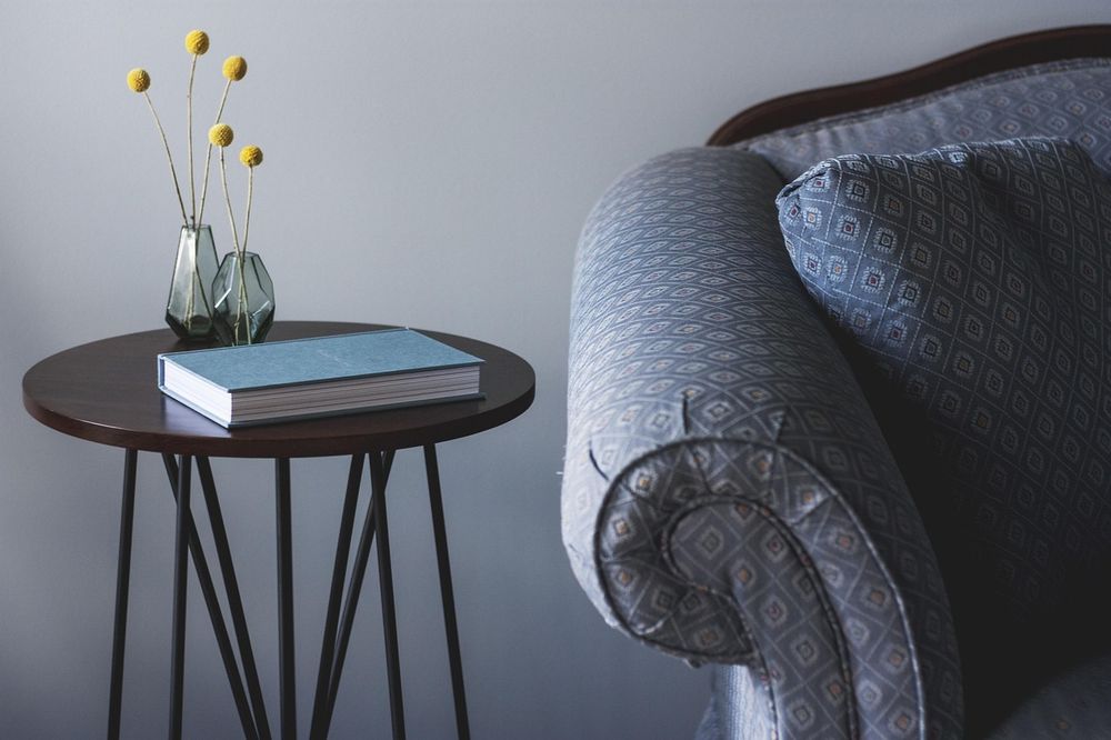 A round wooden side table on black hairpin legs